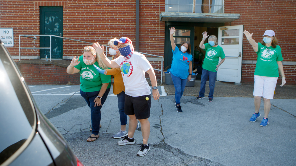 Staff photo by C.B. Schmelter / East Brainerd Elementary staff members wave to some of their students as they come to pick up items at Chattanooga School for the Liberal Arts on Tuesday, April 21, 2020 in Chattanooga, Tenn. Teachers and volunteers made care packages for 250 East Brainerd Elementary students who were displaced by Easter Sunday's tornado. The packages included school materials but also items like Play-Doh, colored pencils and books.