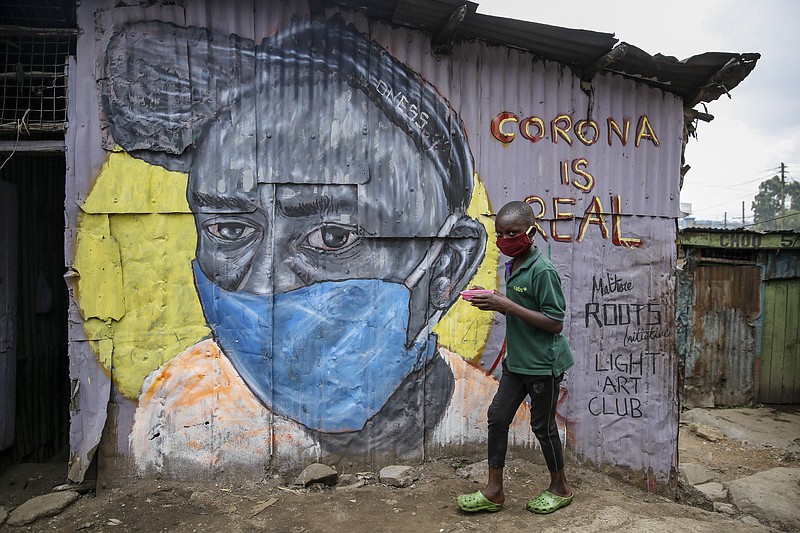 A boy wearing a face mask carries a small bowl of "githeri", or mixed beans and maize, for him to eat as he walks past an informational mural warning people about the risk of the new coronavirus, painted by graffiti artists from the Mathare Roots youth group, in the Mathare slum, or informal settlement, of Nairobi, Kenya Saturday, April 18, 2020. Africa now has more than 1,000 deaths from COVID-19, the Africa Centers for Disease Control and Prevention said Saturday, with 52 of the continent's 54 countries having reported cases. (AP Photo/Brian Inganga)


