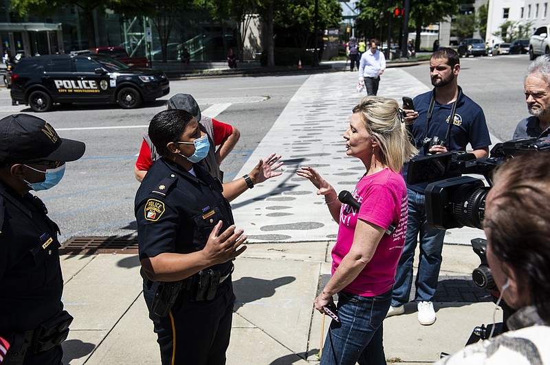 Maj. Ramona Harris talks with Reopen Alabama protestors about proper distancing at the intersection of Decatur Street and Dexter Ave. in downtown Montgomery, Ala., on Tuesday, April 21, 2020. Gov. Kay Ivey said she intends to keep a stay home order to fight the spread of coronavirus in place through April 30, striking a measured approach as some Southern states push to quickly reopen. /The Montgomery Advertiser via AP)


