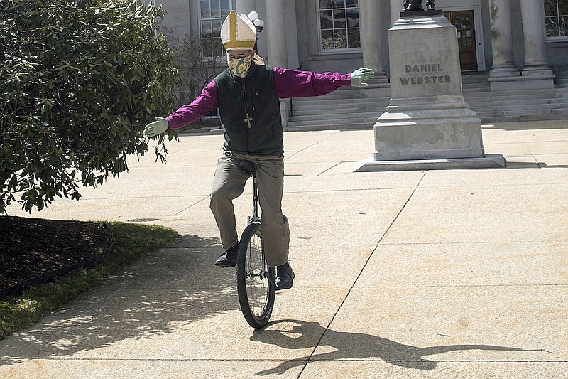 In this April 15, 2020, photo, Bishop of the Episcopal Church of New Hampshire, the Rt. Rev. Robert Hirschfeld, wears his bishop's mitre and mask as he rides outside the State House in Concord, N.H., to raise awareness to keep reducing infection rate and to raise funds for a local charity. (Geoff Forester/Concord Monitor via AP)/The Concord Monitor via AP)


