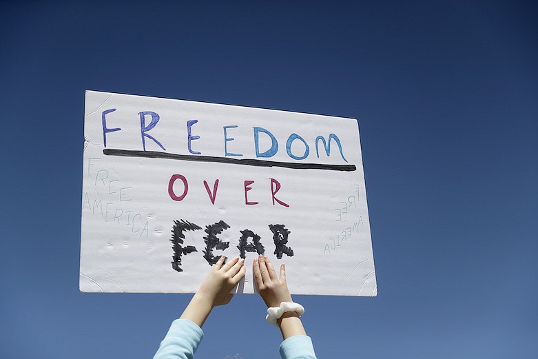 A person holds a sign while gathering with others to protest stay-at-home orders put into place due to the COVID-19 outbreak Tuesday, April 21, 2020, outside the Missouri Capitol in Jefferson City, Mo. Several hundred gathered to protest the restrictions and urge the reopening of businesses closed in an effort to slow the spread of the coronavirus . (AP Photo/Jeff Roberson)