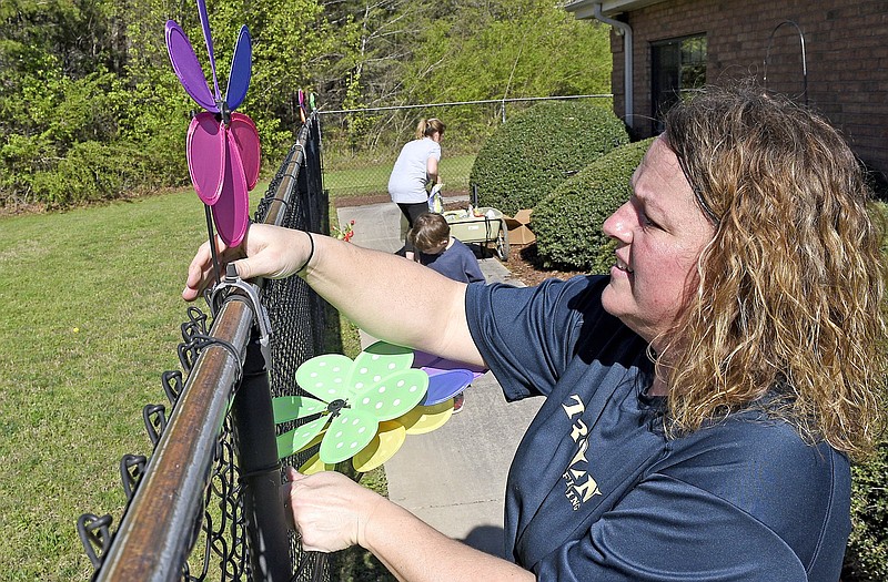 Staff Photo by Robin Rudd / Laura Higgins Bates attaches a pinwheel to the fence outside a resident's window at the Soddy-Daisy Health Care Center. Concerned that the mostly elderly residents at the facility are confined to their rooms during the coronavirus, Bates asked permission to place flower pots, bird feeders and garden art outside their windows. "Our goal [was] to have no social interactions in this process, but still make an impact on those that are shut in," Bates said.