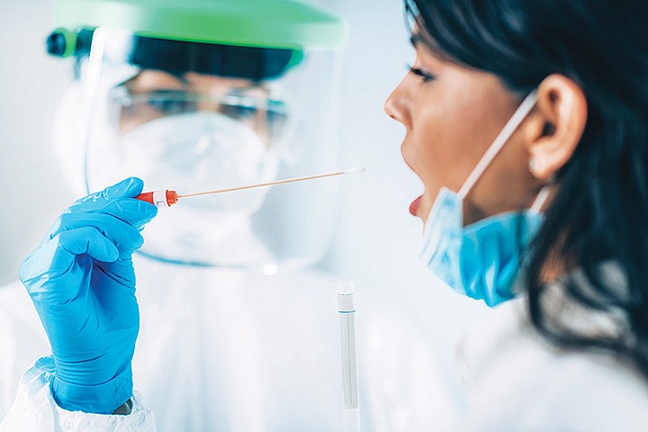 Coronavirus test. Medical worker in protective suite taking a swab for corona virus test, potentially infected young woman. / Getty Images/iStock/microgen