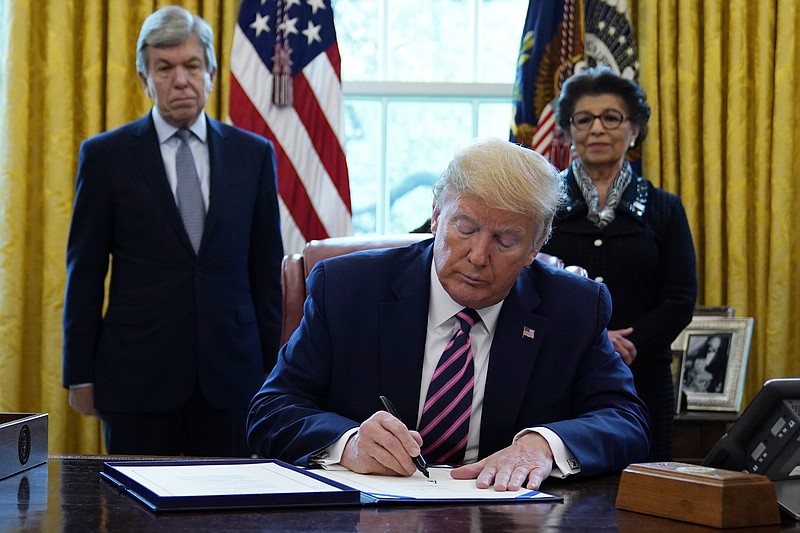 President Donald Trump signs a coronavirus aid package to direct funds to small businesses, hospitals and testing in the Oval Office of the White House on April 24, 2020, in Washington. Sen. Roy Blunt, R-Mo., left, and Jovita Carranza, administrator of the Small Business Administration, look on. (AP Photo/Evan Vucci)