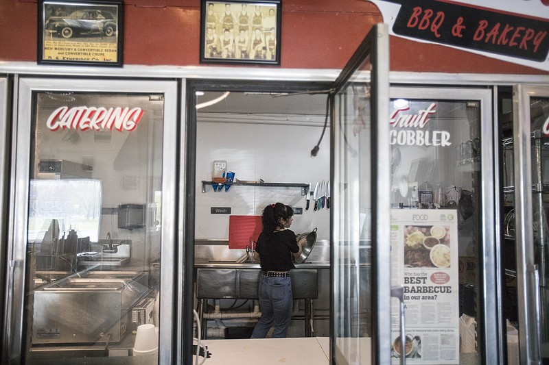 Staff photo by Troy Stolt / Katie Riddle, an employee of Charlie's Quik Stop BBQ and Bakery, washes dishes in the kitchen on Wednesday, April 1, 2020 in Chattanooga, Tenn. Since Mayor Andy Berke's order to suspend dining services temporarily, allowing restaurants to stay open only to provide carry out service, Charlie's has turned their dining room into additional space to service to-go orders.
