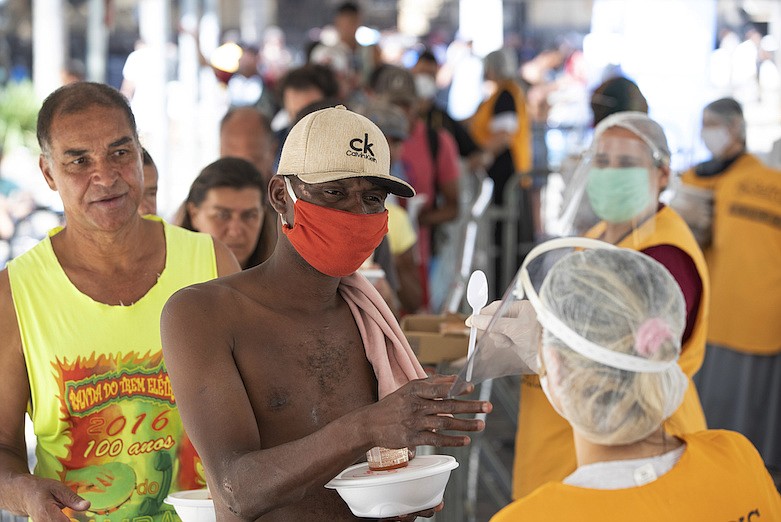 Volunteers from a Christian church serve food to homeless people during a quarantine imposed by the state government to help contain the spread of the new coronavirus in Sao Paulo, Brazil, Monday, April 27, 2020. (AP Photo/Andre Penner)