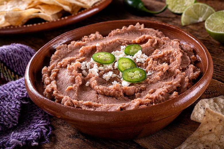 Mexican style refried beans with queso fresco and jalapeno pepper garnish. / Getty Images/iStock/ Fudio