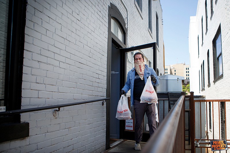 Staff photo by C.B. Schmelter / Ben Carlson carries orders out to cars at The Bitter Alibi on Tuesday, April 28, 2020 in Chattanooga, Tenn. The Bitter Alibi, like most area restaurants, are holding off on allowing dine-in services and just sticking with takeout/curbside and delivery as Chattanooga continues to reopen following the coronavirus shutdown.