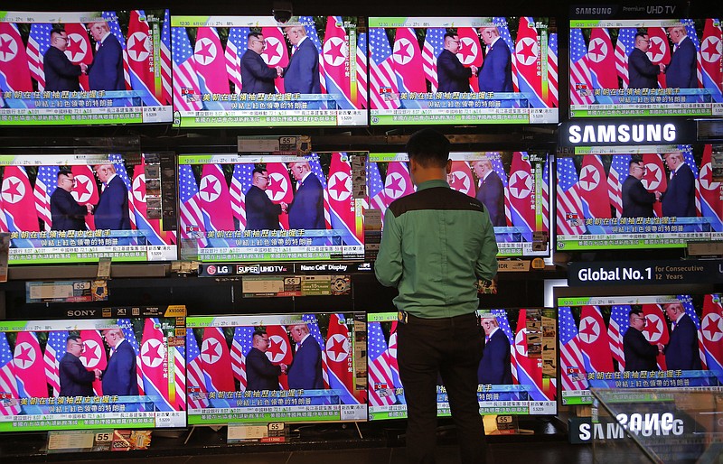 Photo by Vincent Yu of The Assocaited Press / A man watches a TV screen showing U.S. President Donald Trump, right, meeting with North Korean leader Kim Jong Un in Singapore during a news program in Hong Kong on June 12, 2018.