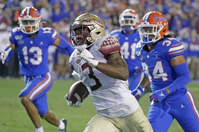 FILE - In this Nov. 30, 2019, file photo, Florida State running back Cam Akers (3) runs for a 50-yard touchdown past Florida linebacker Lacedrick Brunson (34) and defensive back Donovan Stiner (13) during the second half of an NCAA college football game in Gainesville, Fla. Akers was selected by the Los Angeles Rams in the second round of the NFL football draft Friday, April 24, 2020. (AP Photo/John Raoux)