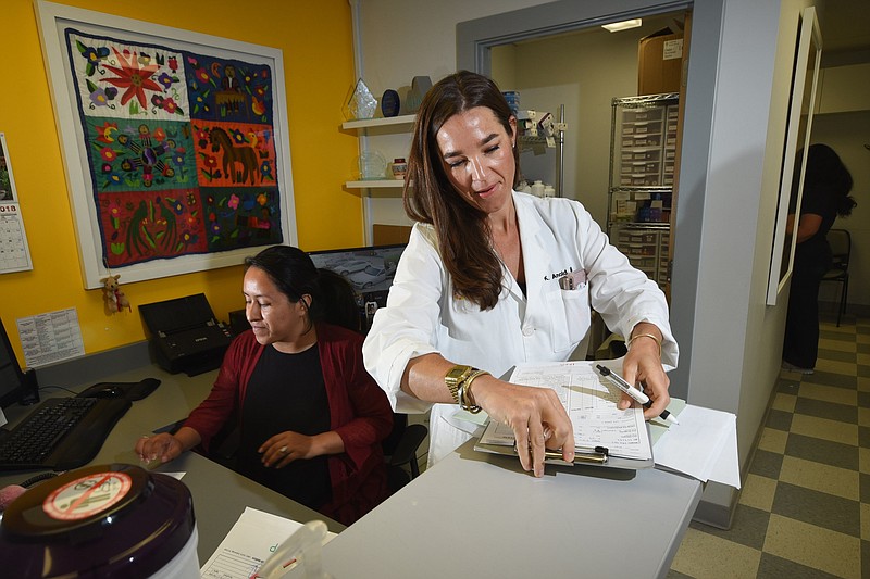 Staff file photo by Tim Barber / Dr. K. Rodney Arnold, MD, works in her Clinica Medicos office on East 23rd Street in this file photo taken in 2018. Mindy Perez works at the desk, at left.