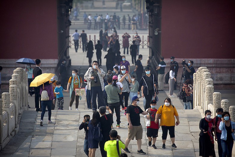 Visitors wearing face masks to protect against the new coronavirus walk through the Forbidden City in Beijing, Friday, May 1, 2020. The Forbidden City reopened beginning on Friday, China's May Day holiday, to limited visitors after being closed to the public for more than three months during the coronavirus outbreak. (AP Photo/Mark Schiefelbein)