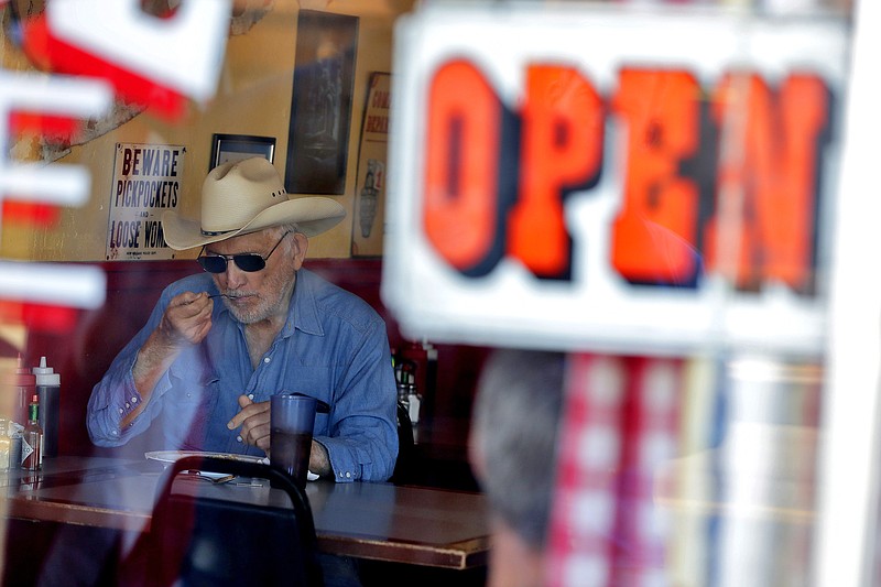 A customer eats inside the Horseshoe Cafe Friday, May 1, 2020, in Wickenburg, Ariz. A few small businesses reopened in defiance of Arizona Gov. Doug Ducey's decision to extend a statewide stay-at-home order for another two weeks in. The Gov. extended the stay at home order in an effort to combat the COVID-19 coronavirus outbreak. (AP Photo/Matt York)