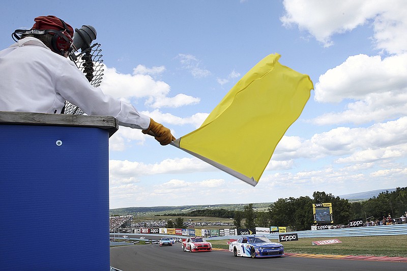 AP photo by Mel Evans / A track marshall waves a yellow caution flag during a NASCAR Xfinity Series race on Aug. 6, 2016, at Watkins Glen International in New York.