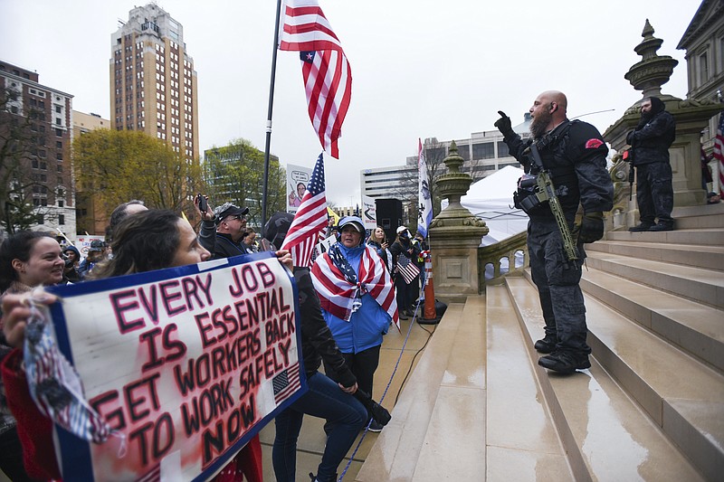 Matthew Dae Smith, Lansing State Journal via AP / Gun-toting members of the Michigan Liberty Militia, including Phil Robinson, right, join protesters at a rally at the state Capitol in Lansing, Michigan last week. Hoisting American flags and handmade signs, protesters returned to the state Capitol to denounce Gov. Gretchen Whitmer's stay-home order and business restrictions due to COVID-19.