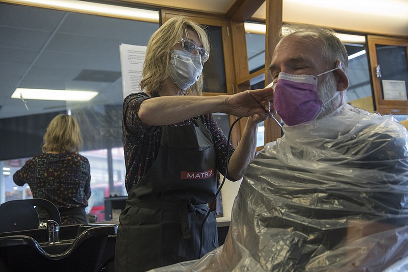 Staff photo by Troy Stolt / Town and Country Barber Shop and Salon owner Marti Brown cuts her husband Ron's hair inside of their shop located at 125 North Market Street, on Tuesday, May 5, 2020 in Chattanooga, Tenn. Barber shops and salons across Tennessee will be reopening Wednesday, with strict regulations in order to maintain social distancing practices put in place to stop the spread of coronavirus.