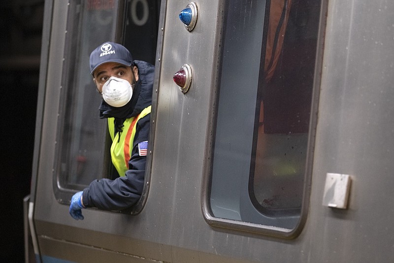 FILE - In this April 24, 2020, file photo, a subway train driver wearing a protective mask operates the doors of a Massachusetts Bay Transportation Authority's Blue Line subway car at Maverick Station in Boston. Public transit systems nationwide are grappling with plummeting ridership and revenue during the coronavirus pandemic. (AP Photo/Michael Dwyer, File)