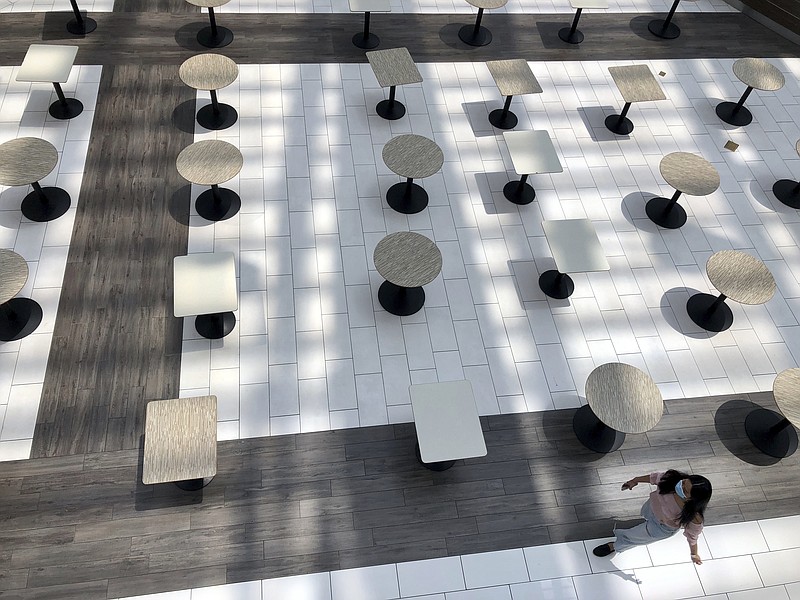 A woman wearing a protective mask walks through the mostly empty food court as Alabama's largest shopping mall, the Riverchase Galleria reopened in Hoover, Ala., Tuesday, May 5, 2020. Dozens of stores, including major retailers, remained closed as the mall opened for business for the first time during the coronavirus pandemic. (AP Photo/Jay Reeves)


