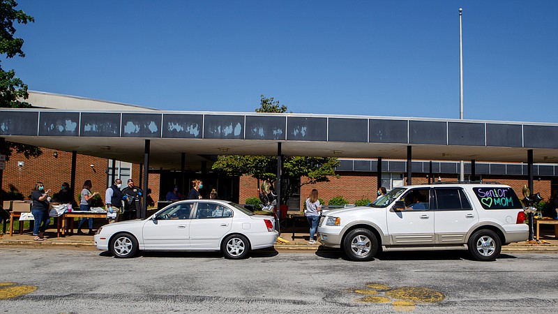 Staff photo by C.B. Schmelter / Cars line up at Hixson High School to turn in school property and pick up graduation items on Thursday, May 7, 2020 in Hixson, Tenn. High school seniors were able to pick up their caps and gowns and other senior year relics in drive-thru format; they were also given the opportunity to see friends and teachers for the first, and possibly last, time before graduation.