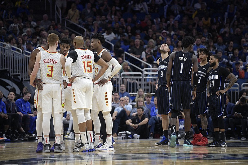 AP photo by Phelan M. Ebenhack / Players for the Atlanta Hawks, left, and Orlando Magic huddle on the court during an officials' review on Dec. 30, 2019, in Orlando, Fla. The NBA suspended its 2019-20 season on March 11 due to concerns about the coronavirus pandemic.