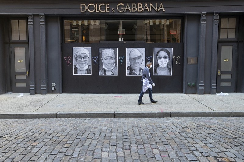 A man wearing a face mask to protect against the coronavirus walks past a closed Dolce & Gabbana store, Thursday, May 7, 2020, in the Soho neighborhood of Manhattan in New York. Nearly 3.2 million laid-off workers applied for unemployment benefits last week as the business shutdowns caused by the coronavirus outbreak deepened the worst U.S. economic catastrophe in decades. (AP Photo/Mary Altaffer)



