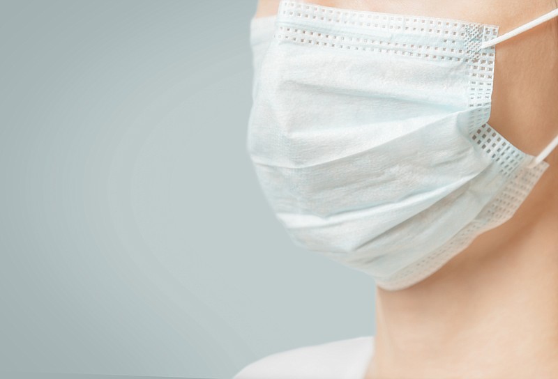 Unrecognizable woman in medical protective mask against virus and infection diseases, close-up. Copy-space in left part of image. mask tile / Getty Images
