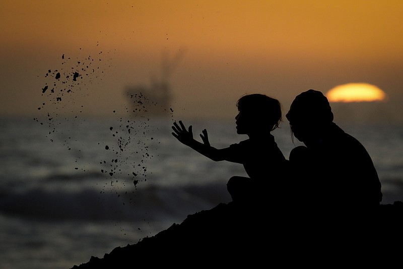 The Associated Press / Youngsters play in the sand in late April in Huntington Beach, Calif., before the governor closed beaches.