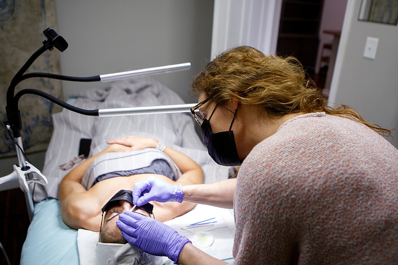 Staff photo by C.B. Schmelter / Owner and esthetician Jessica West works on a brow tint at Skin and Brow Room on Gunbarrel Road on Friday. West applied for and received federal relief funding for her small business, which reopened on Wednesday after being closed for six weeks.