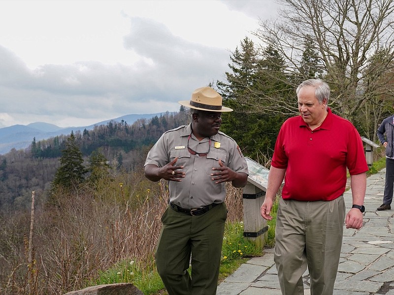 This Wednesday, May 6, 2020 image from a tweet by Interior Secretary David Bernhardt, the Interior Secretary talks with Cassius Cash, the park superintendent, as he visits National Parks Service employees at Great Smoky Mountains National Park. While the Interior Secretary asked visitors to social distance when the park reopens on May 9, neither Bernhardt nor park staff wore face masks in the photos, as they talked and walked inches apart during his visit on Tuesday, May 5. (National Parks Service via AP)