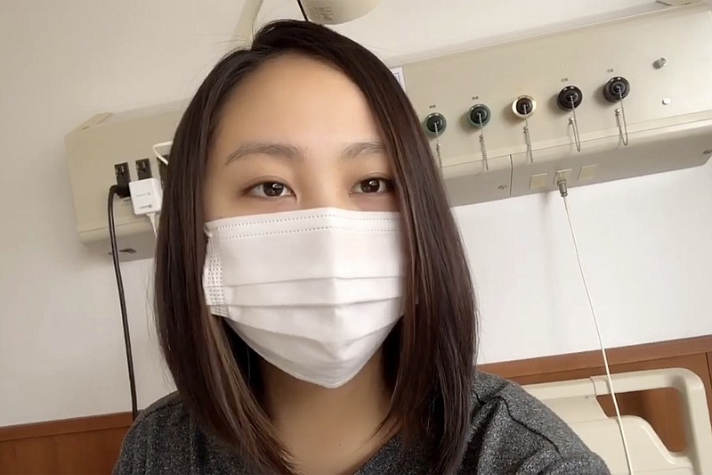 In this April 19, 2020, image made from the Youtube account of Arisa Kadono, she speaks to her smartphone video at a hospital, in Himeji, western Japan. Soon after Kadono tested positive for the coronavirus and hospitalized in early April, her friends let her know that groundless rumors were circulating. (Arisa Kadono via AP)