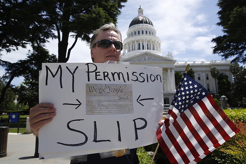 Photo by Rich Pedroncelli of The Associated Press / Dru Vincent and about a dozen other protesters, calling for the end of California Gov. Gavin Newsom's stay-at-home orders, demonstrated at the state Capitol in Sacramento on Wednesday, April 22, 2020. The California Highway Patrol announced that it is temporarily banning rallies at the state Capitol and other state facilities due to the pandemic. The change came after hundreds of protestors gathered on the Capitol grounds Monday, many without masks or following recommendations to remain six feet apart to slow the spread of the coronavirus.