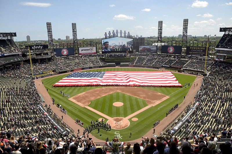 FILE - In this July 4, 2019, file photo, an American Flag is unfurled in the outfield during the playing of the National Anthem before the start a baseball game between the Chicago White Sox and the Detroit Tigers in Chicago. Major League Baseball owners gave the go-ahead Monday, May 11, 2020, to making a proposal to the players' union that could lead to the coronavirus-delayed season starting around the Fourth of July weekend in ballparks without fans, a plan that envisioned expanding the designated hitter to the National League for 2020. (AP Photo/Mark Black, File)