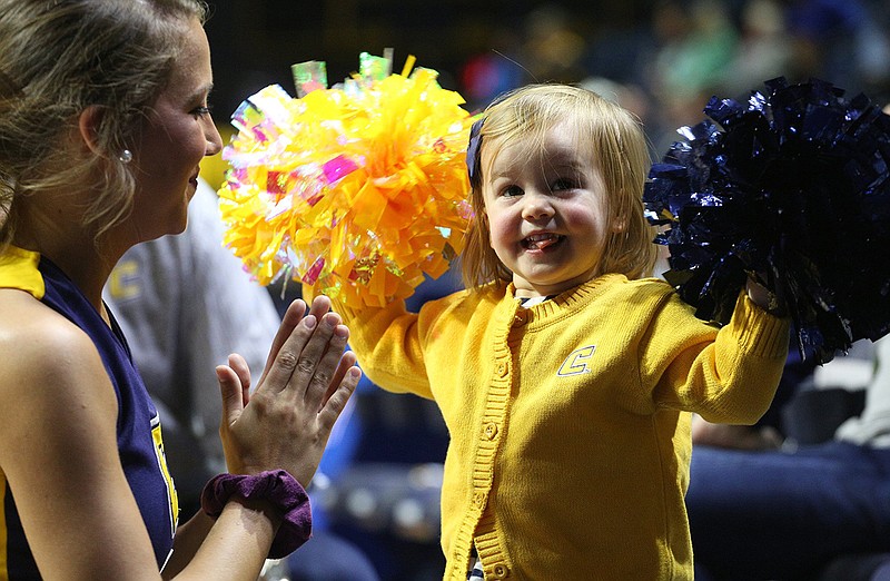 Staff photo / UTC cheerleader Abby McClure encourages 2-year-old Lowe Norton on the sideline during a men's basketball game against Bryan College on Dec. 21, 2018 at McKenzie Arena.