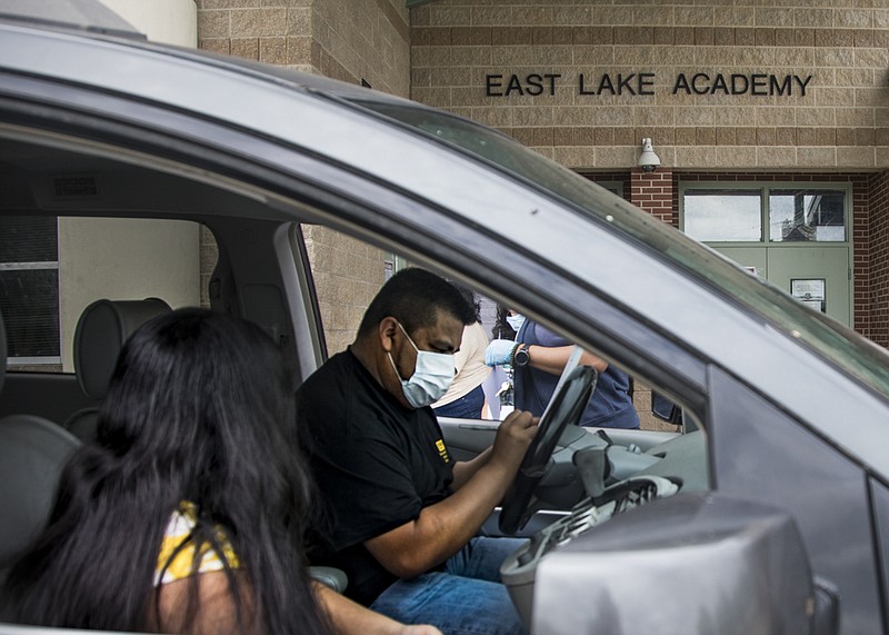 Staff photo by Troy Stolt / Evelio Valasquez fills out a sign out sheet for his daughter Luceny, 11, who is finishing the sixth grade at East Lake Academy on Thursday, May 14, 2020, in Chattanooga, Tenn. Approximately one in six cases of coronavirus in Hamilton County have come from the 37407 zip code, which includes the East Lake and Clifton Hills neighborhoods, though the area only makes up three percent of the County's population.