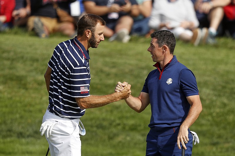 AP photo by Alastair Grant / Dustin Johnson, left, and Rory McIlroy shake hands on the 16th green at the end of a fourball match on the opening day of the 42nd Ryder Cup on Sept. 28, 2018, near Paris. Johnson and McIlroy headline a charity match Sunday at Seminole Golf Club in Juno Beach, Fla., an event that will raise millions for COVID-19 relief and be the first live golf on television since the pandemic shut down sports worldwide in mid-March.