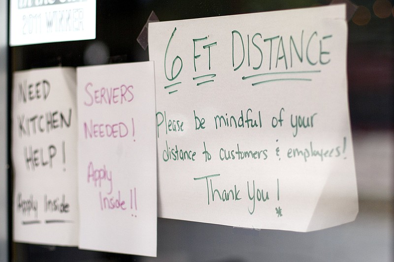 Staff photo by C.B. Schmelter / A sign highlighting social distancing is seen on the door at Purple Daisy Picnic Cafe on Monday, April 27, 2020 in Chattanooga, Tenn. R