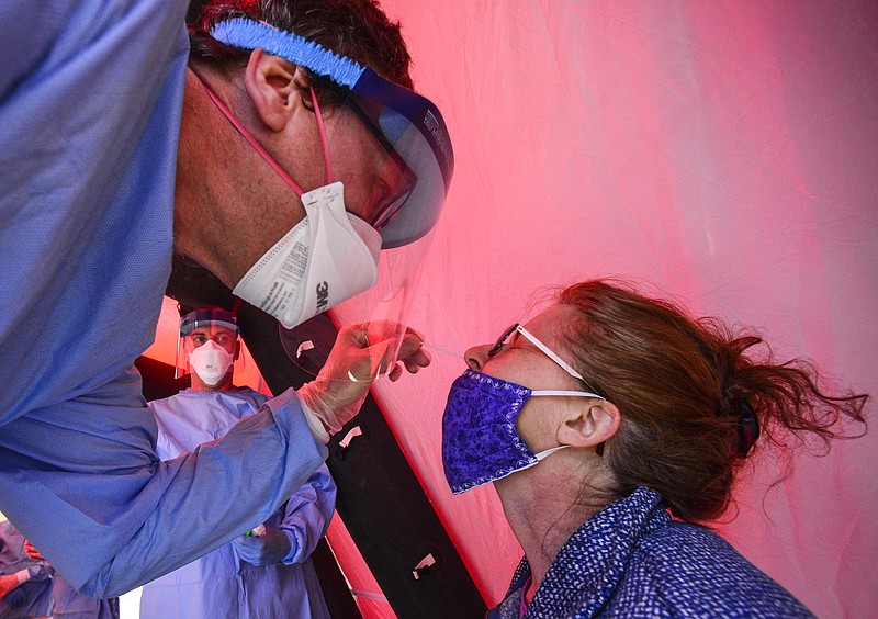 Steve Morlock, of Rescue Inc., puts a COVID-19 testing swab up the nasal passage of Sharon Branand, of West Chesterfield, N.H., during a pop-up COVID-19 testing clinic at the Brattleboro Union High School's parking lot, in Brattleboro, Vt., Thursday, May 14, 2020. The clinics are part of the state's efforts to ramp up testing and prevent the spread of COVID-19. (Kristopher Radder/The Brattleboro Reformer via AP)