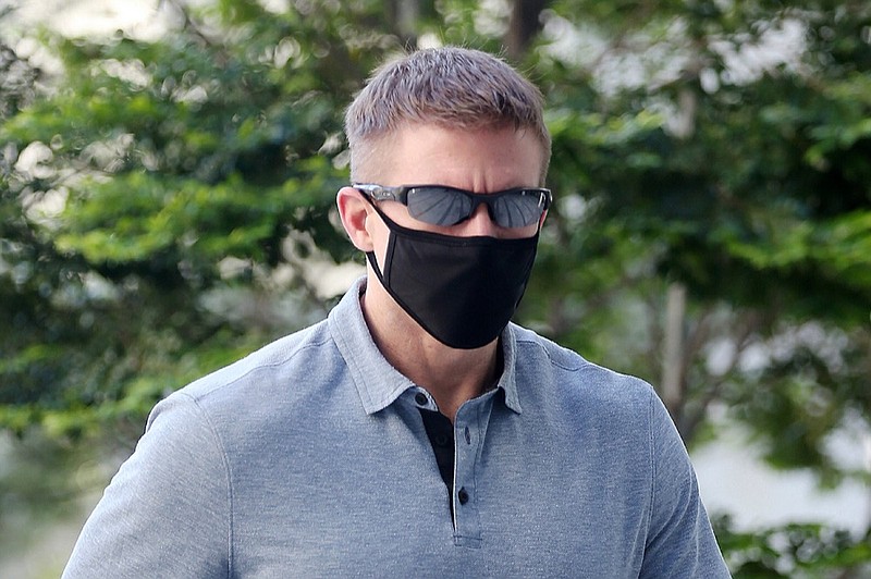 In this May 13, 2020, photo, Brian Dugan Yeargan, wearing a face mask and sunglasses, walks outside the Singapore State Court in Singapore. The 44-year-old American pilot has been jailed for four weeks for breaching a quarantine order in Singapore. Local media reported that Brian Dugan Yeargan was sentenced by a court Wednesday, May 13 for leaving his hotel room for three hours to buy masks and a thermometer. (The Straits Times via AP)


