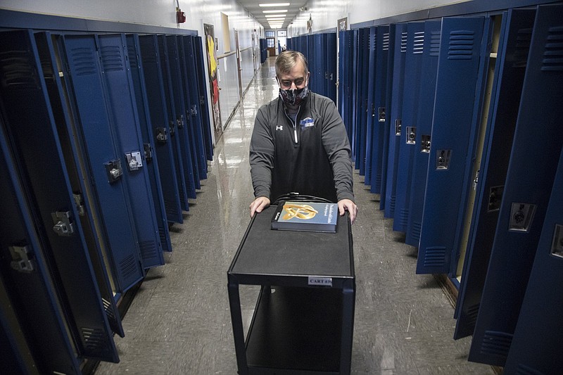 Staff photo by Troy Stolt / Chattanooga School for Arts and Sciences (CSAS) high school math teacher Bill Bowser pushes a cart down a hallway on the third floor of the school on Wednesday, May 13, 2020 in Chattanooga, Tenn. The official last day of school for Hamilton County had originally been set for May 21, but eventually the school board changed that date to May 15, after Governor Bill Lee recommended the change because of coronavirus in 