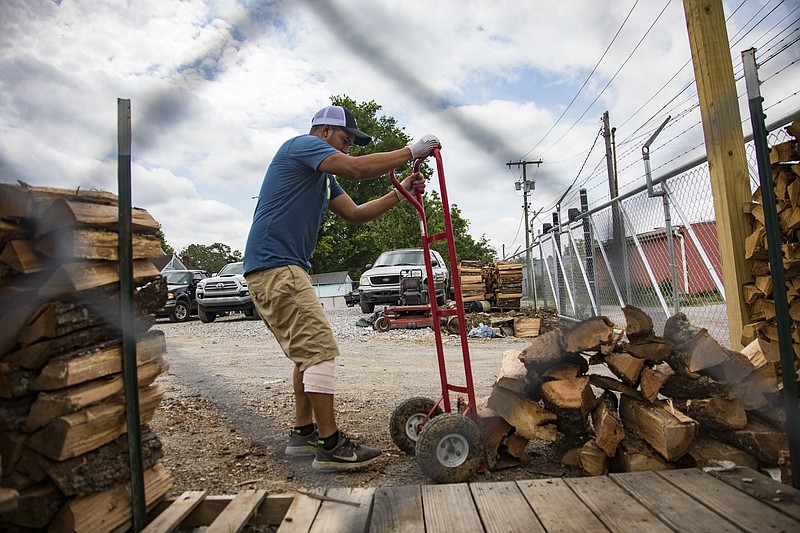 Staff photo by Troy Stolt / Gilber Perez moves wood to stack off of a dolly at Garcia Tree Service on 37th Street on Thursday, May 14, 2020 in Chattanooga, Tenn. Approximately one in six cases of coronavirus in Hamilton County have come from the 37407 ZIP code, which includes the East Lake and Clifton Hills neighborhoods, though the area only makes up three percent of the county's population.