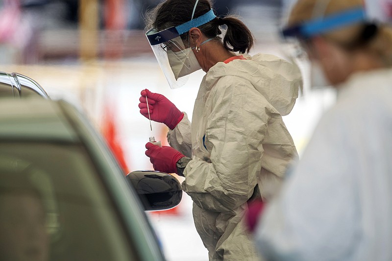 The Associated Press / A health care worker drops a specimen collection into a container after testing a motorist for the COVID-19 virus at a community testing site in the parking lot of La Flor de Jalisco #2 in Gainesville, Georgia, last weeka.