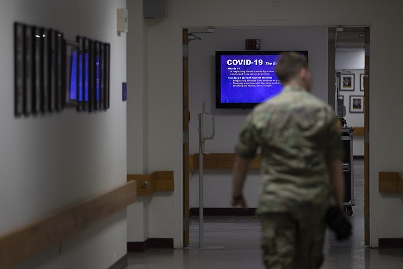 FILE - In this March 25, 2020, file photo a member of the U.S. Army walks down the hall toward a monitor displaying COVID-19 safety information in Fort Meade, Md. As of last week, the Army had already exceeded its retention goal of 50,000 soldiers for the fiscal year ending in September, re-enlisting more than 52,000 so far. (AP Photo/Carolyn Kaster, File)