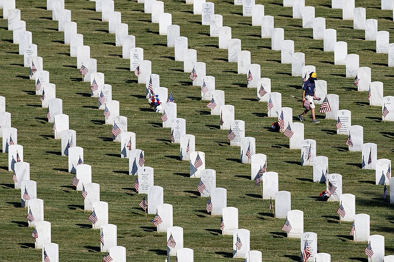 Staff photo by C.B. Schmelter / A Cub Scout carries a stack of American flags while walking through the graves during the Boy Scouts of America Annual Memorial Day Ceremony at the Chattanooga National Cemetery on Saturday, May 25, 2019 in Chattanooga, Tenn.