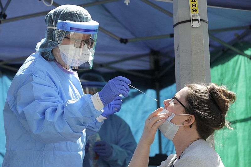 Tina Nguyen, left, a nurse at at the International Community Health Services clinic in Seattle's International District, takes a nose swab sample from Mindy Balk, an ICHS employee, during walk- and drive-up testing for COVID-19, Friday, May 15, 2020. As testing supplies for coronavirus have become more abundant, the clinic has been able to offer testing to anyone in the community by appointment if they are experiencing symptoms. (AP Photo/Ted S. Warren)


