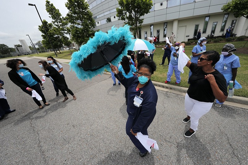 Healthcare workers at New Orleans East Hospital wave handkerchiefs and dance to a jazz serenade, as a tribute for their care for COVID-19 patients, by the New Orleans Jazz Orchestra, outside the hospital in New Orleans, Friday, May 15, 2020. A New York woman collaborated with the New Orleans Jazz Orchestra to put on what she calls a stimulus serenade to give moral support to front-line hospital workers and COVID-19 patients in New Orleans (AP Photo/Gerald Herbert)

