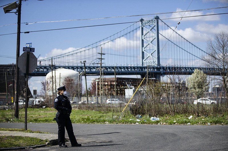 FILE - In this April 1, 2020, file photo, a Camden County police officer wears a protective mask as she waits to direct people to a COVID-19 testing facility in view of the Benjamin Franklin Bridge in Camden, N.J. Public health officials in at least two-thirds of U.S. states are sharing the addresses of people who have the coronavirus with first responders. Supporters say the measure is designed to protect those on the front line, but it's sparked concerns of profiling in minority communities already mistrustful of law enforcement. (AP Photo/Matt Rourke, File)


