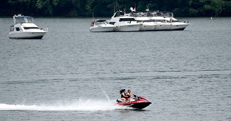 A couple on a personal watercraft speed past large boats anchored in Chickamauga Lake in May, 2019.