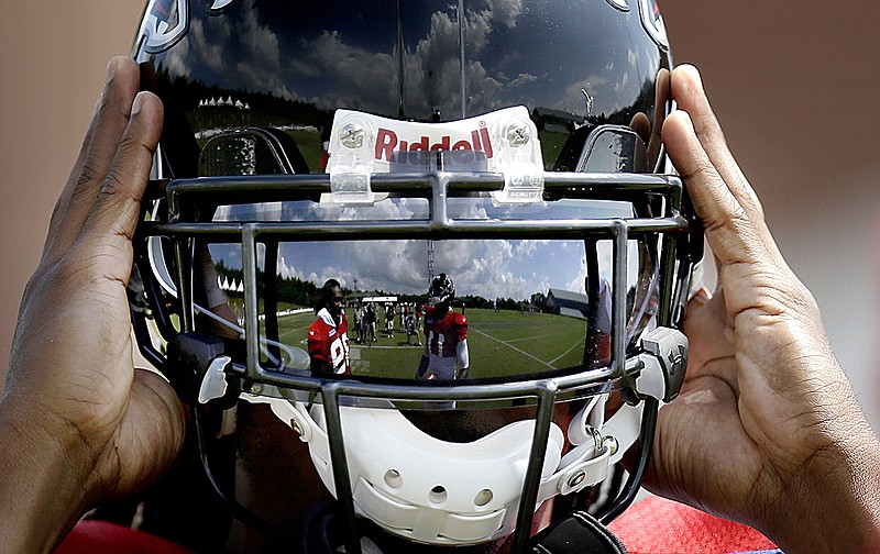 AP photo by David Goldman / Atlanta Falcons running back Steven Jackson, left, and wide receiver Julio Jones are reflected in the visor of teammate Roddy White as he puts his helmet on during training camp on Aug. 1, 2013, in Flowery Branch, Ga. While visor shields are not uncommon in the NFL, the league is studying an entirely new type of face guard for helmets that would function similar to a surgical mask, a possibility that interests a league trying to ensure its 2020 season happens amid the coronavirus pandemic.