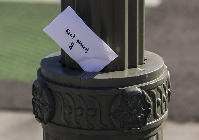 FILE - In this April 1, 2020, file photo, a paper envelope written with the words "Rent Money $" is left tucked in a lighting pole in the Boyle Heights east district of the city of Los Angeles. (AP Photo/Damian Dovarganes, File)


