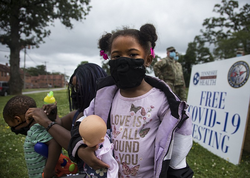 Staff photo by Troy Stolt / Faith Pruitt, 5, stands outside the East Lake Courts Community Center as her mother Dominique tries to put a mask on her two-year-old brother Nehemiah so that they could receive a free COVID-19 test from the Tennessee National Guard on Thursday, May 21, 2020 in Chattanooga, Tenn.